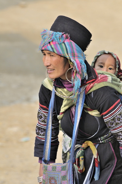 Bébé hmong curieux, sur le dos de sa maman