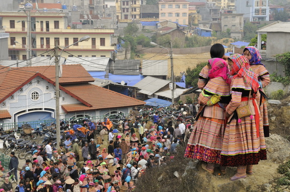 Sur le promontoire, quatre jeunes hmongs bariolées observent le marché